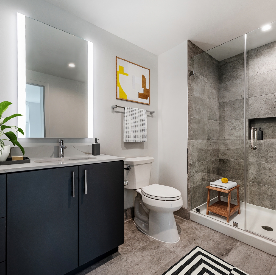 Model bathroom at our apartments in Washington DC, featuring stone pattern floor tiles and sliding glass doors.